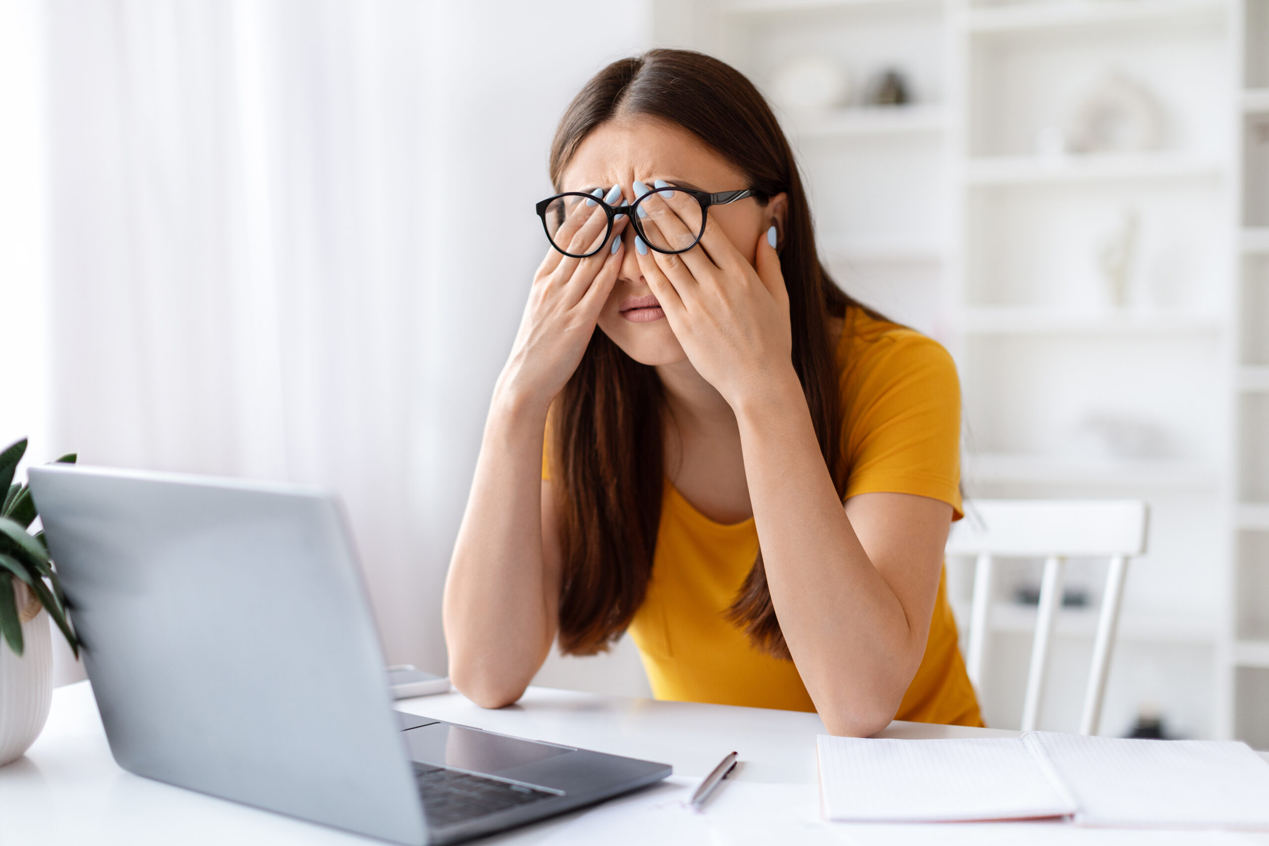 Exhausted Asian woman rubbing tired eyes, suffering from eyestrain after using laptop, korean female freelancer sitting at desk in contemporary home office, having health problems, free space